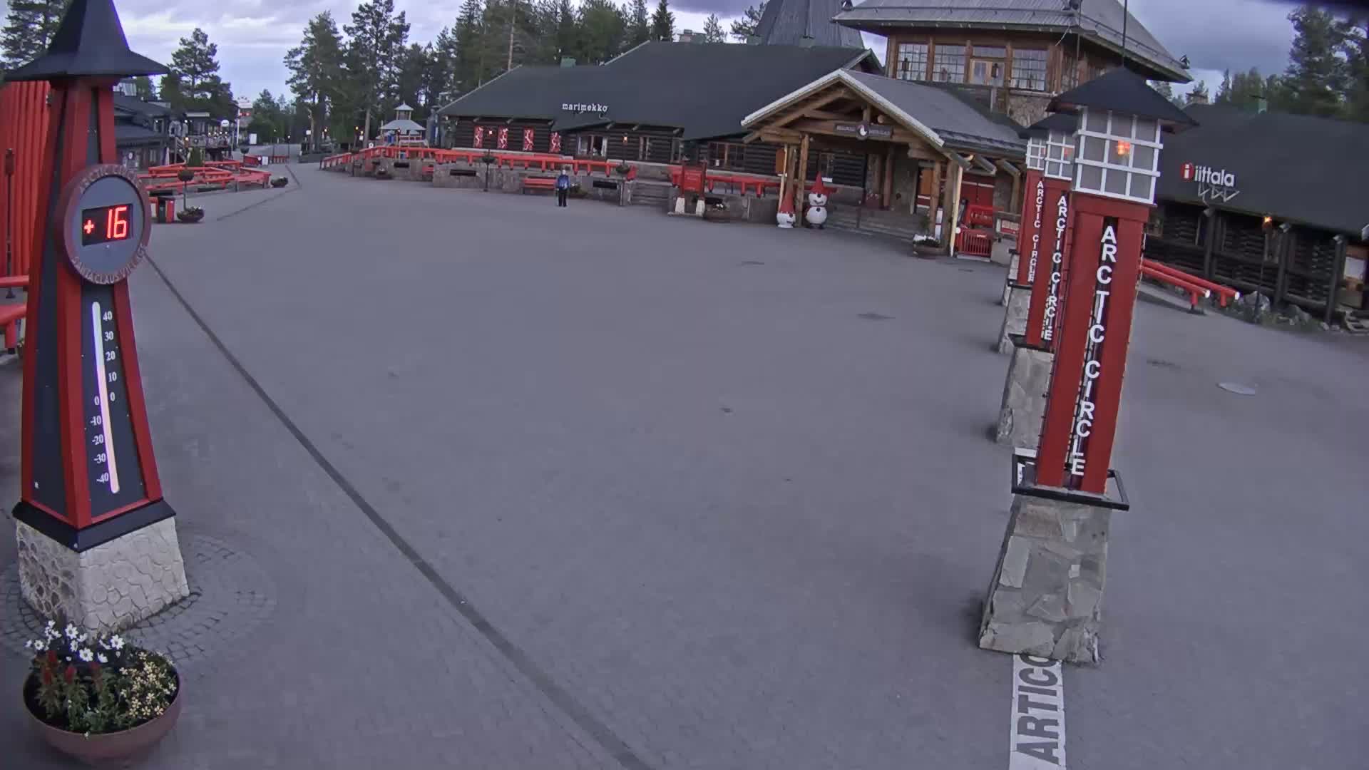 An overcast outdoor scene shows a paved plaza with several red and white Arctic Circle markers, a thermometer displaying 16 degrees, and a building in the background.