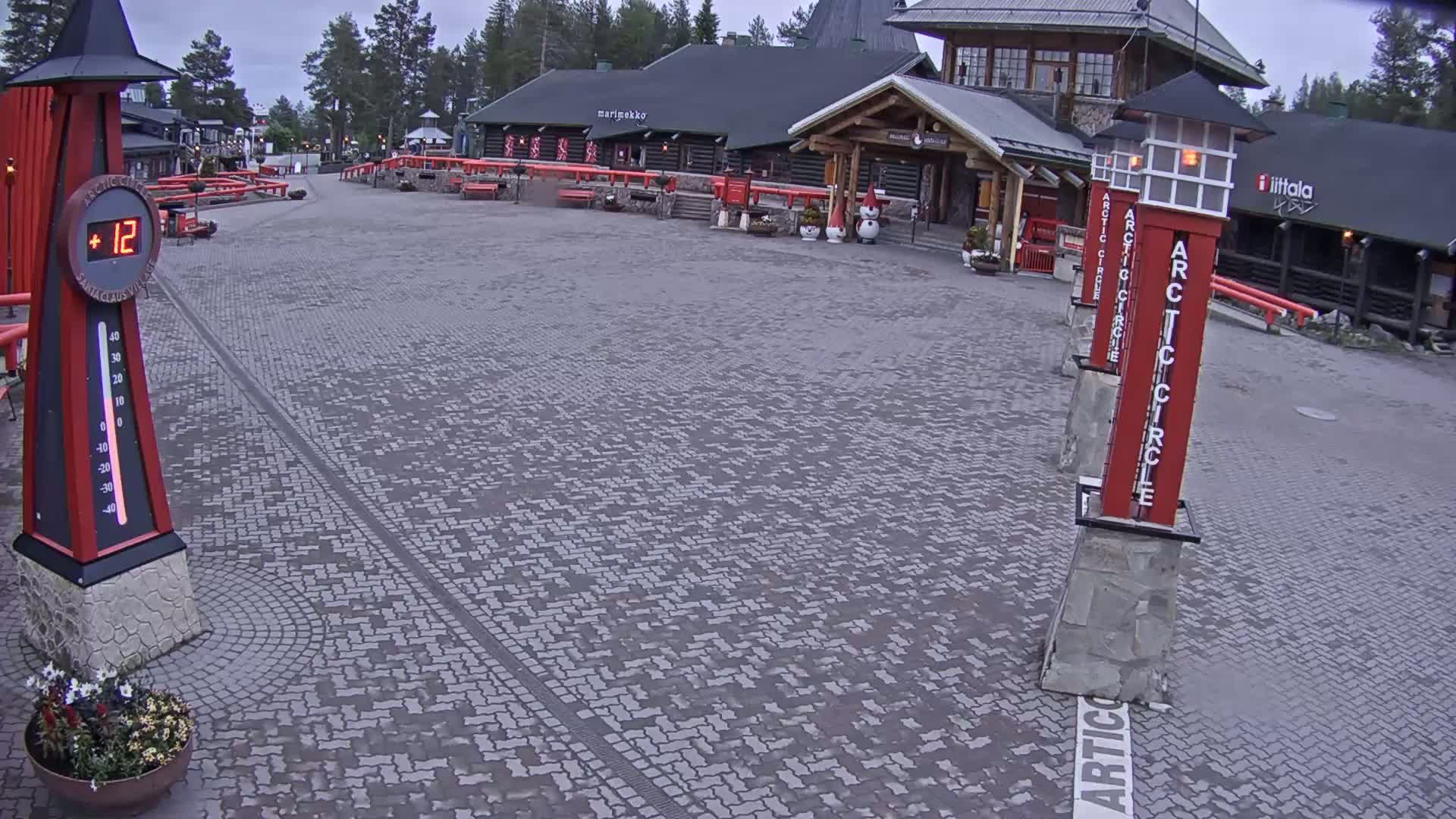 A paved plaza with several buildings, including a log cabin-style structure, under an overcast sky.