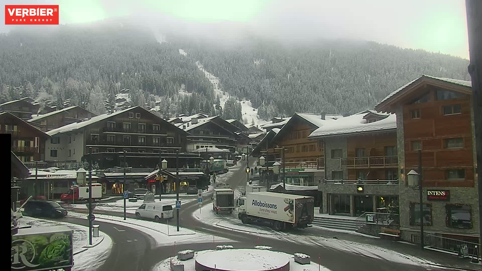 A snow-covered village nestled in a mountain valley under an overcast sky.