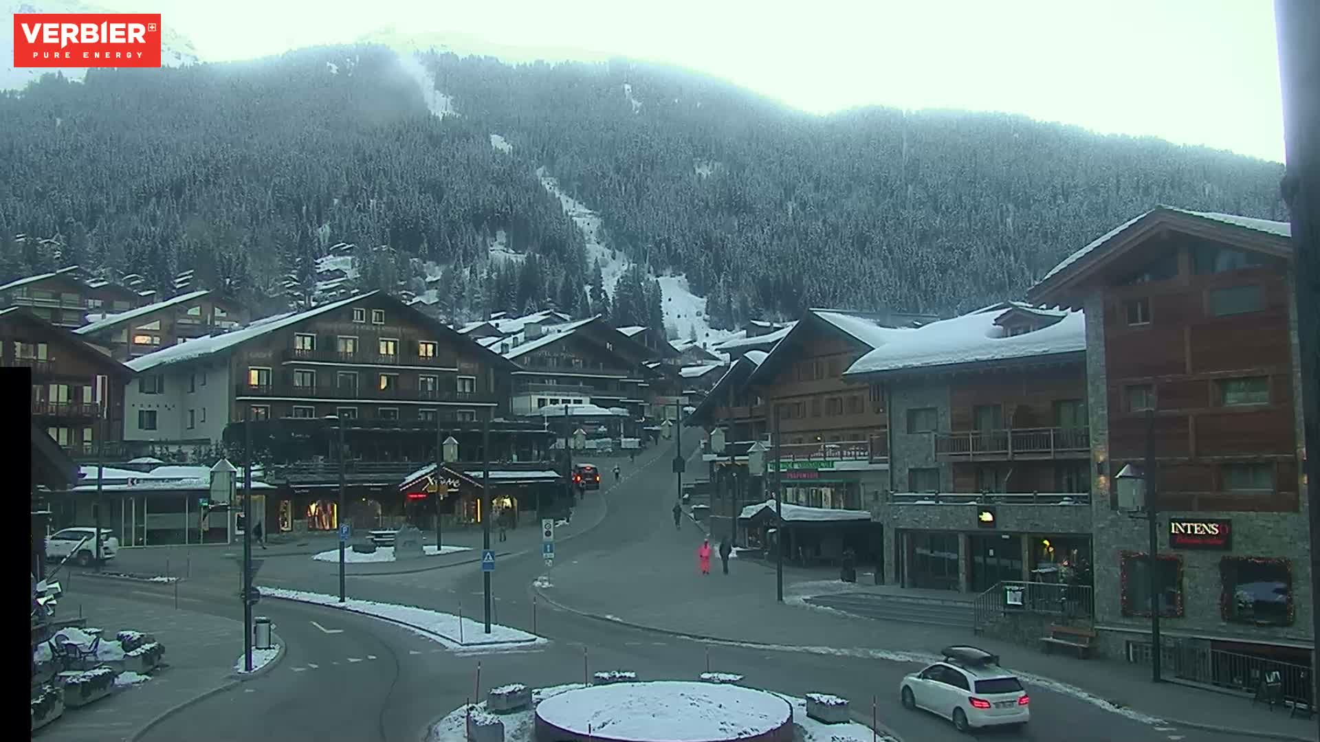 A snow-covered village nestled in a mountain valley under an overcast sky.