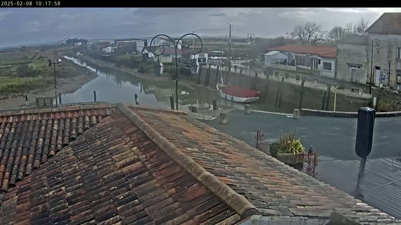 A tiled roof overlooks a calm waterway in a small village on an overcast day.