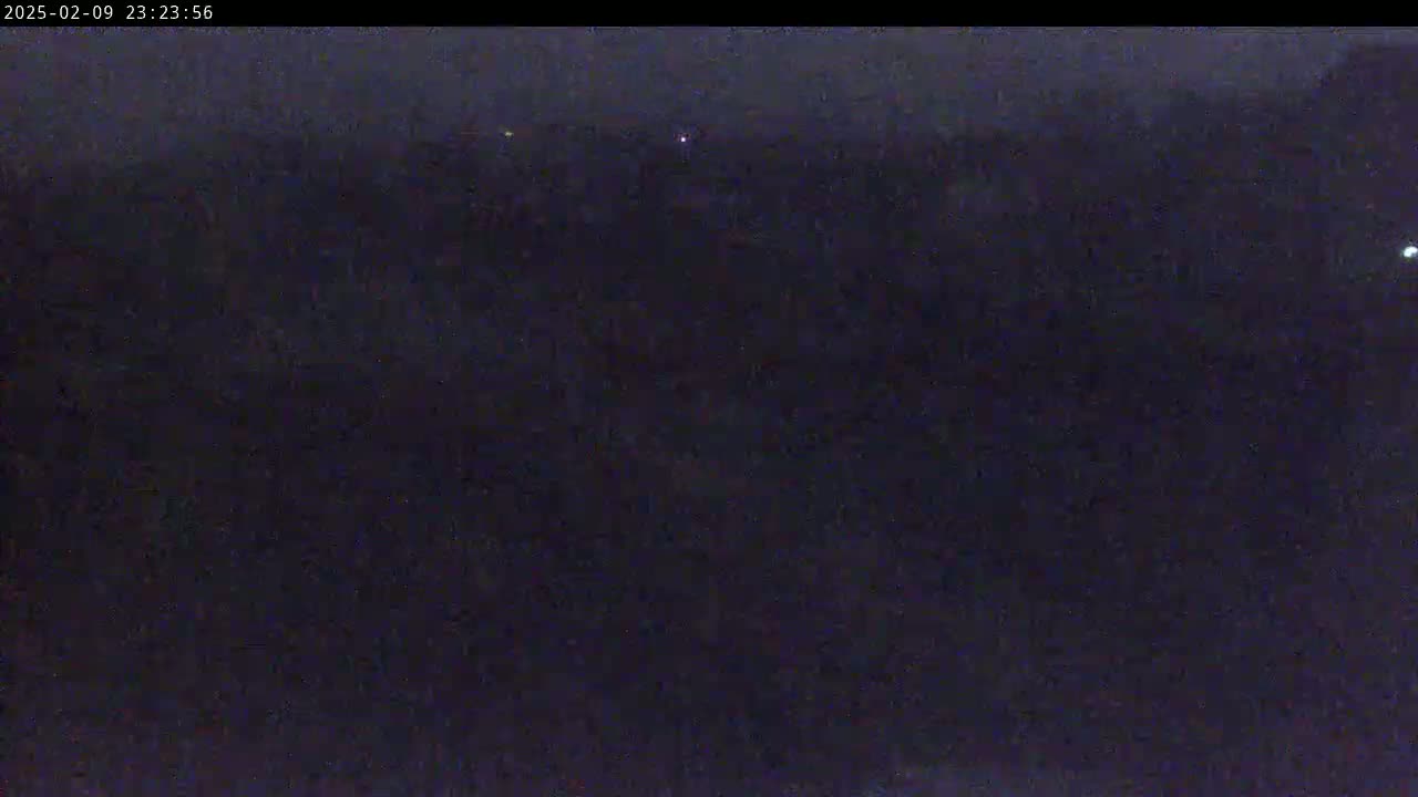 A dark, nighttime view of a landscape with a few distant, faint lights.