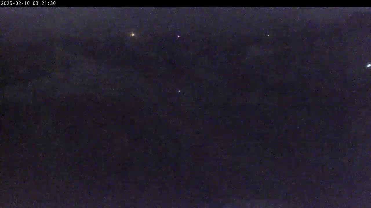 A dark, nighttime scene shows a few distant lights against a mostly dark sky.
