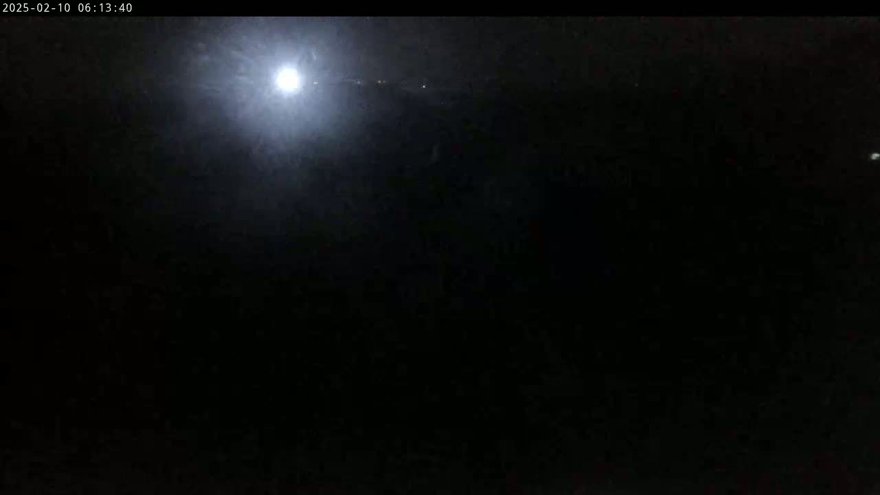 A bright moon shines in a dark, nighttime sky.