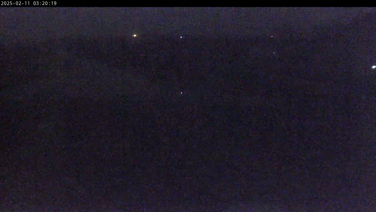 A dark, nighttime scene shows several small, distant lights against a largely black sky.