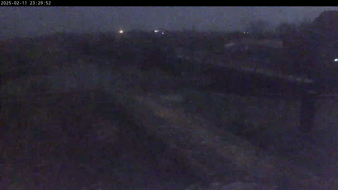 A dark, nighttime view of a mostly obscured landscape under a cloudy sky.