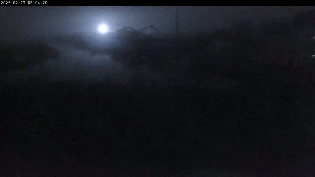 A dimly lit, foggy scene at night shows a dark object in the middle distance, illuminated by a bright moon.