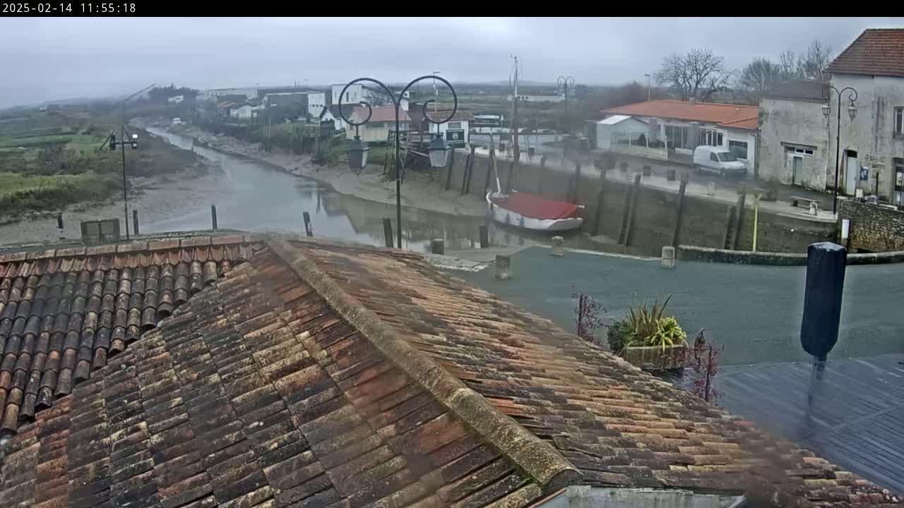 A tiled roof overlooks a calm waterway in a small village on an overcast day.