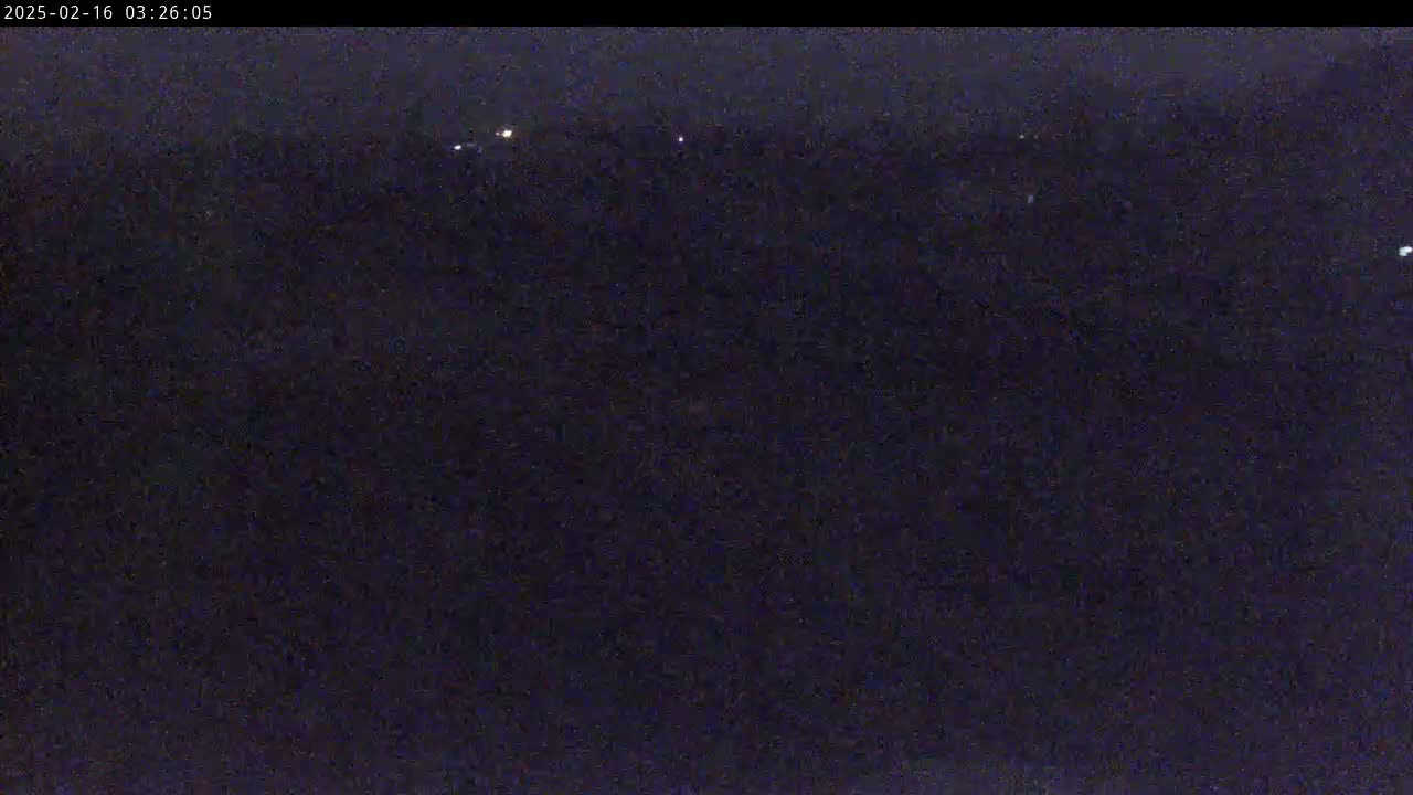A dark, nighttime scene shows a few distant lights in the far background under a dark sky.