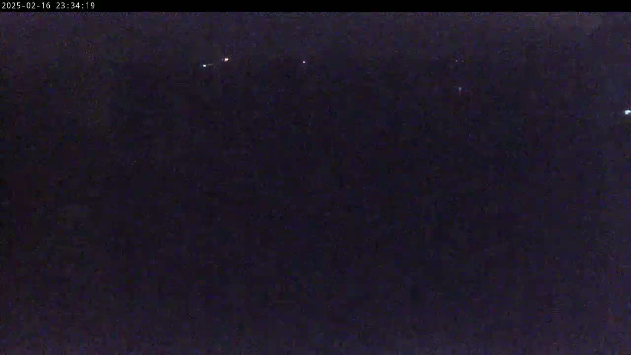 A nighttime, dark image shows several faint lights in the distance.