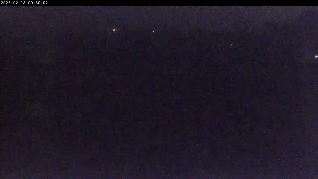 A dark, nighttime scene shows a few small, distant lights against a mostly black sky.
