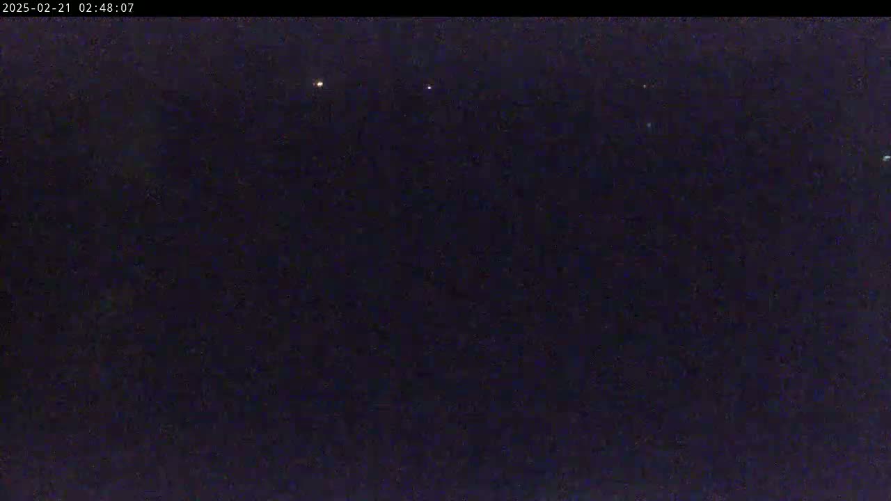 A dark nighttime scene shows a few distant, faint lights against a mostly black sky.