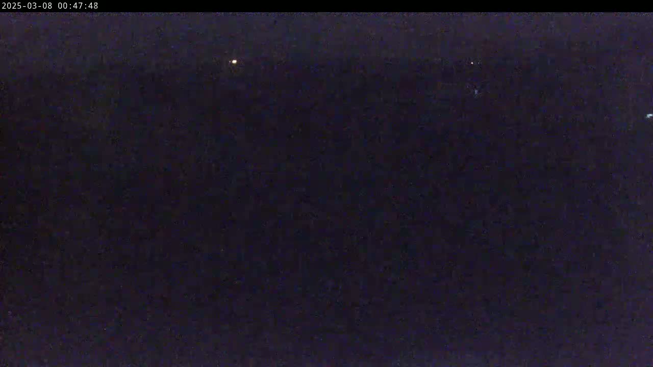 A nighttime outdoor scene shows a dark, mostly featureless expanse with a few distant, faint lights.
