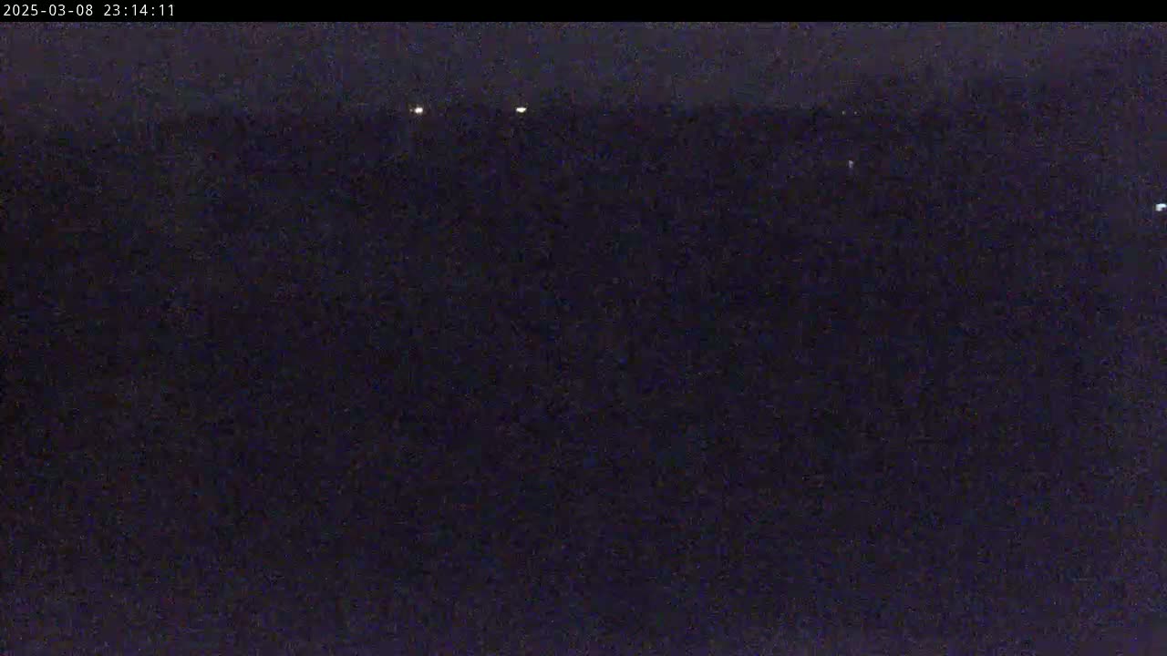 A dark, nighttime scene shows several small, distant lights in the far horizon.