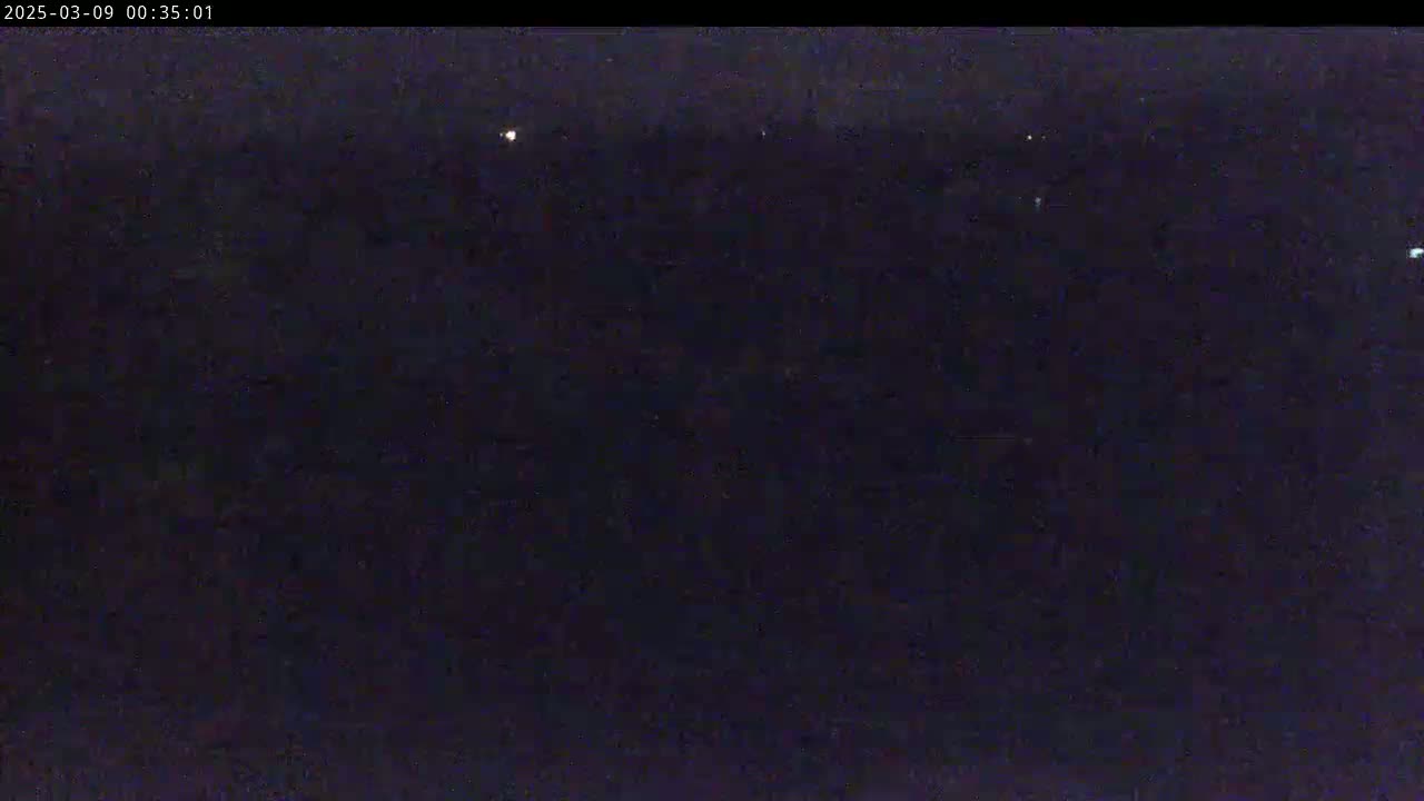 A dark, nighttime scene shows a few distant lights in an otherwise black sky.