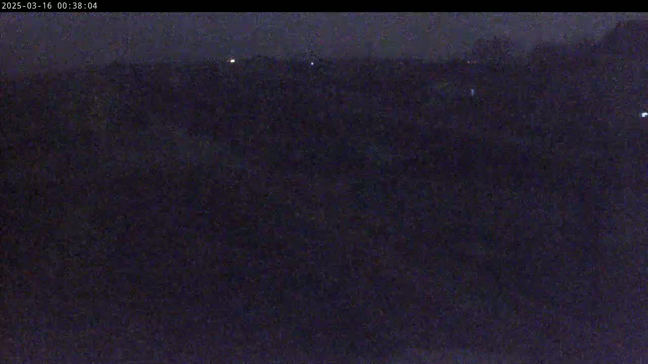 A dark, nighttime scene shows a mostly obscured landscape with a few distant, faint lights.