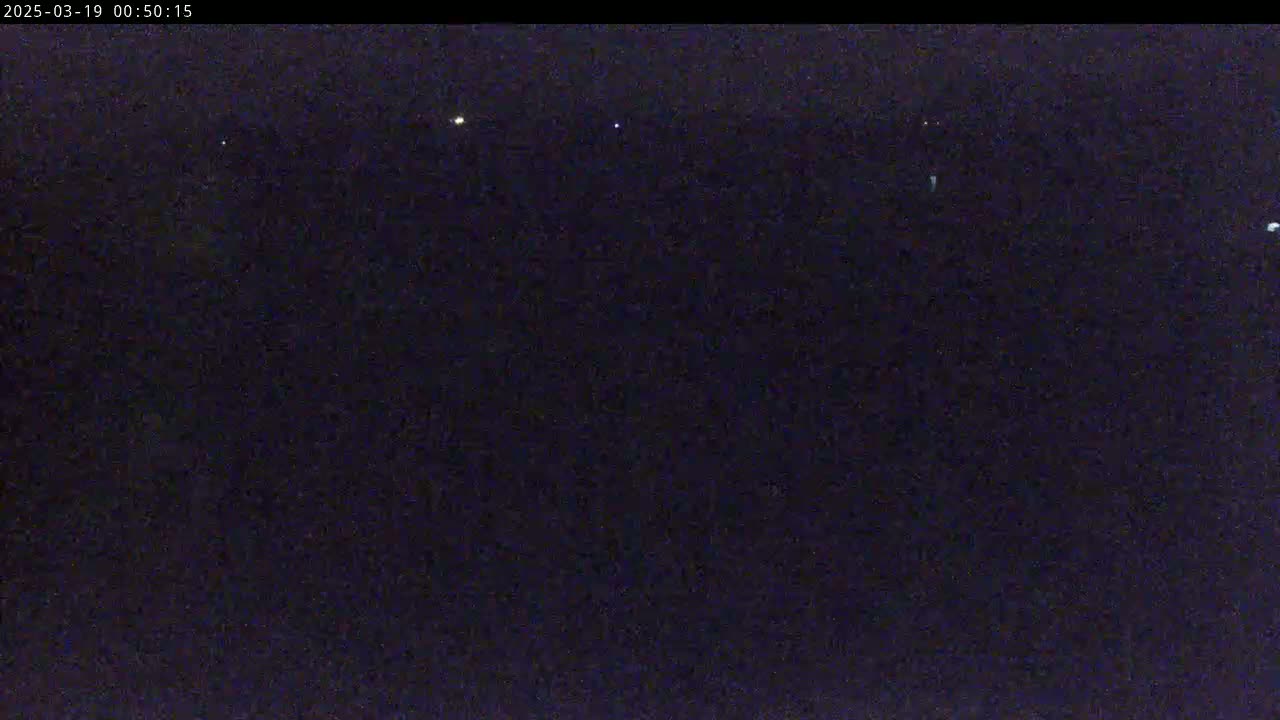 A dark, nighttime scene shows a few distant, faint lights against a mostly black background.