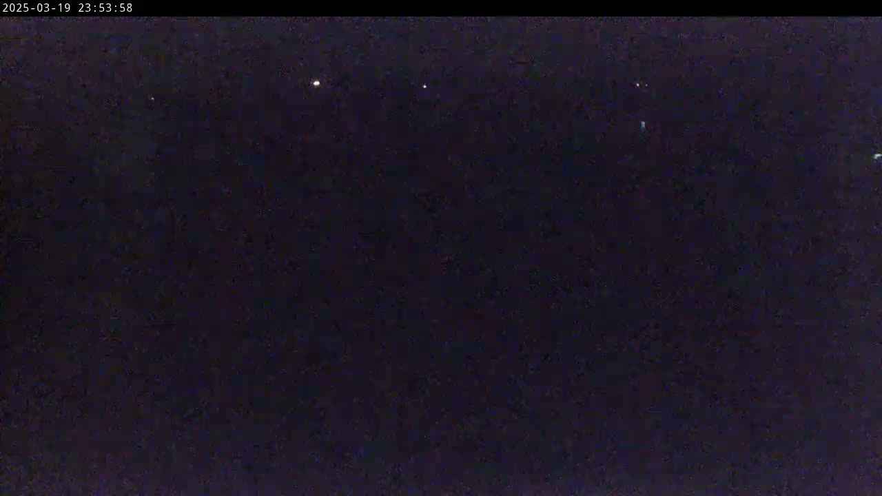 A nighttime image shows a dark sky with a few faint lights visible in the distance.
