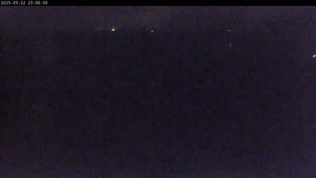 A dark, nighttime scene shows a few distant lights in an otherwise black sky.