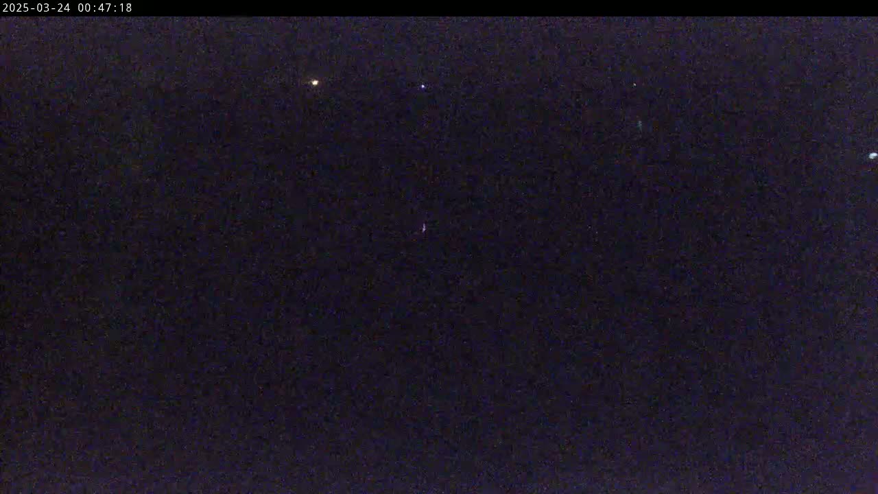 A dark, nighttime scene shows several faint lights in the distance against a mostly black sky.