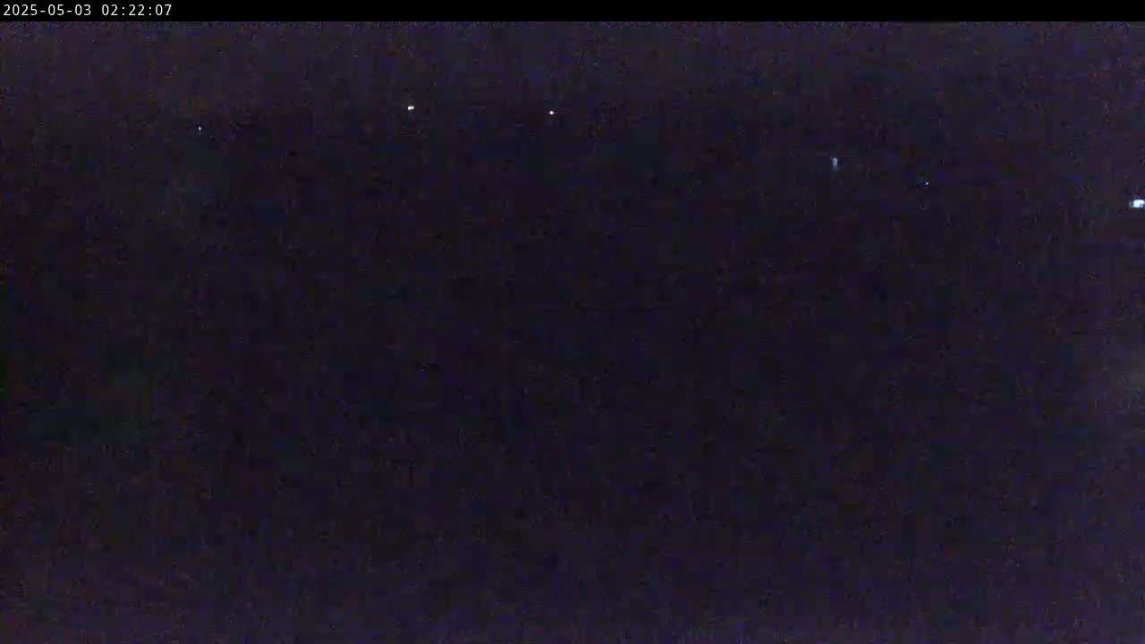 A dark, nighttime outdoor scene shows a few distant lights in the darkness.
