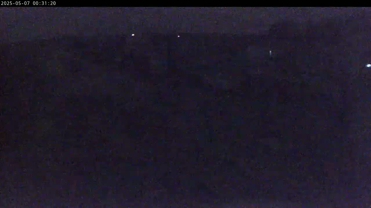 A dark, nighttime scene shows a few distant lights against a mostly featureless, dark background.