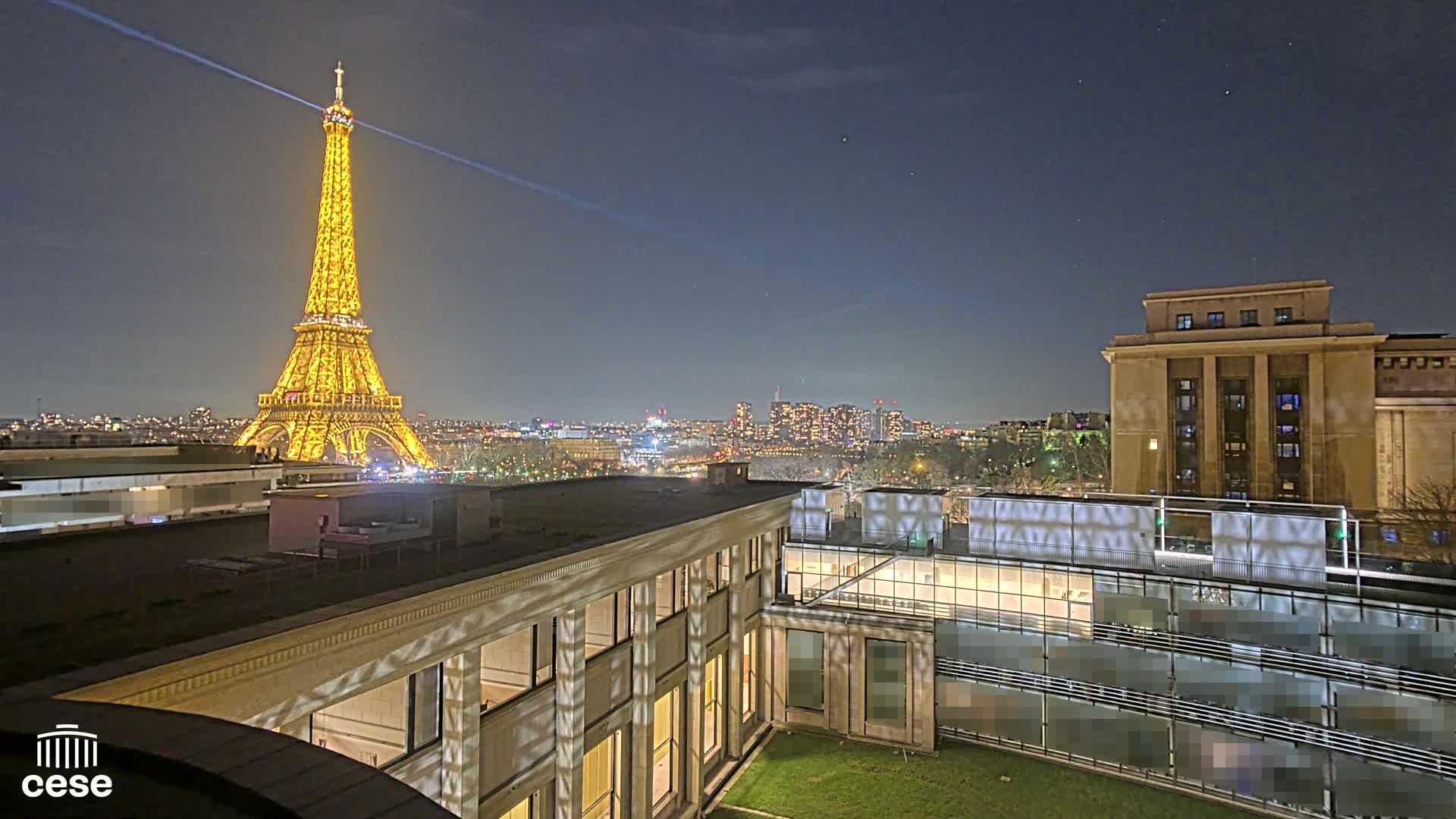 A nighttime view of the Eiffel Tower illuminated, a cityscape, and a building with a courtyard.