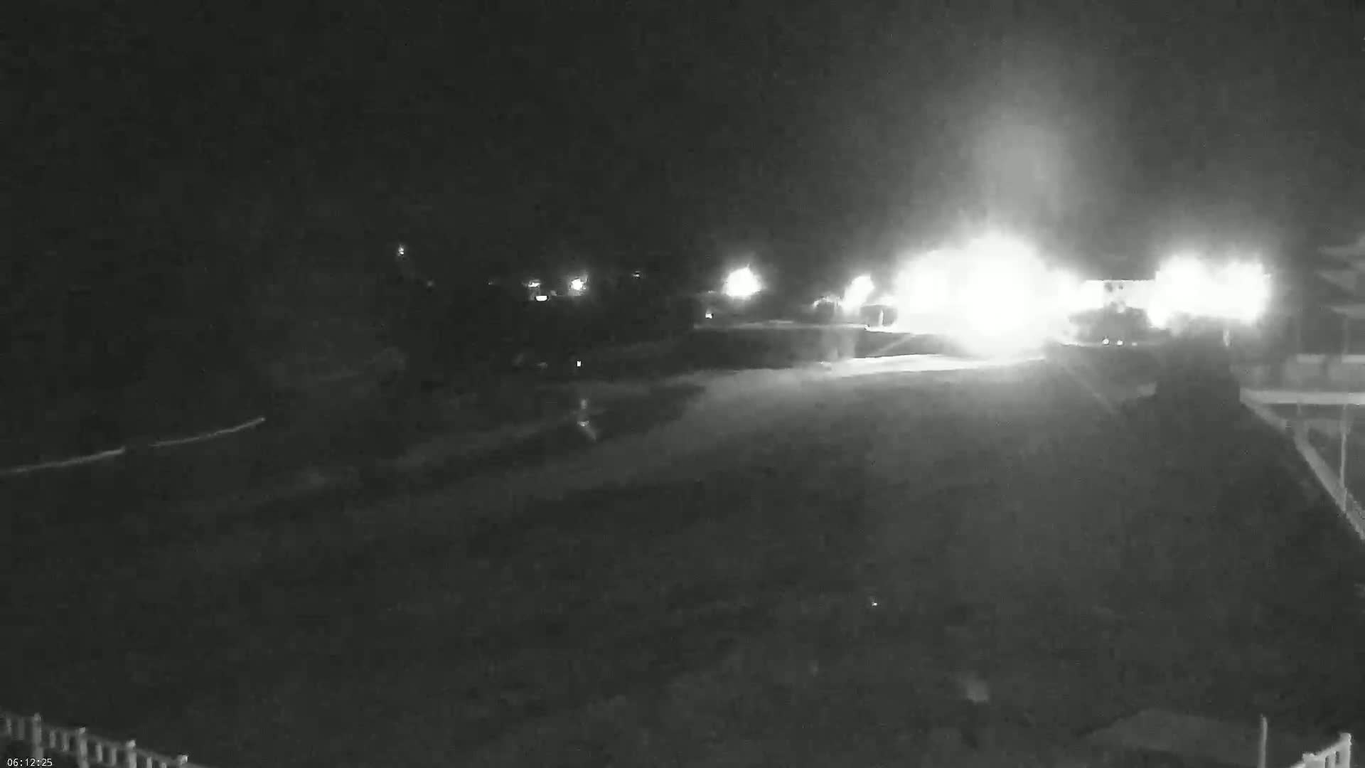 A nighttime, low-light view of a paved area with bright lights in the distance.