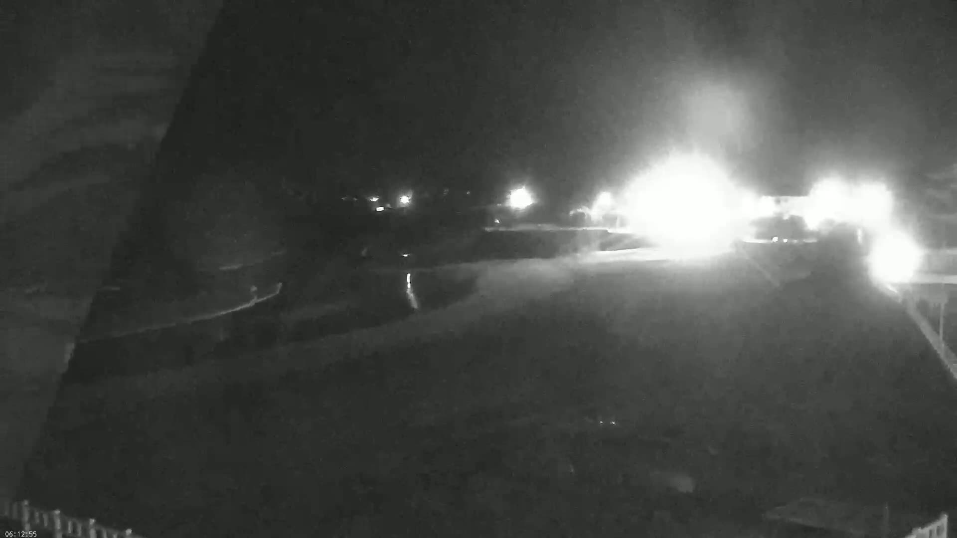 A nighttime, low-light view of a road with bright headlights approaching from the distance.