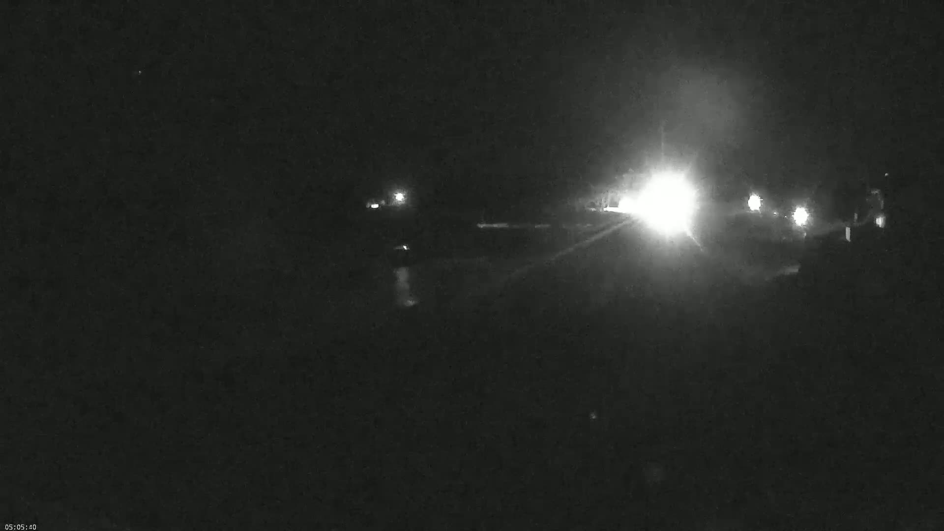 A nighttime, low-light image shows a roadway with vehicle headlights visible in the distance.