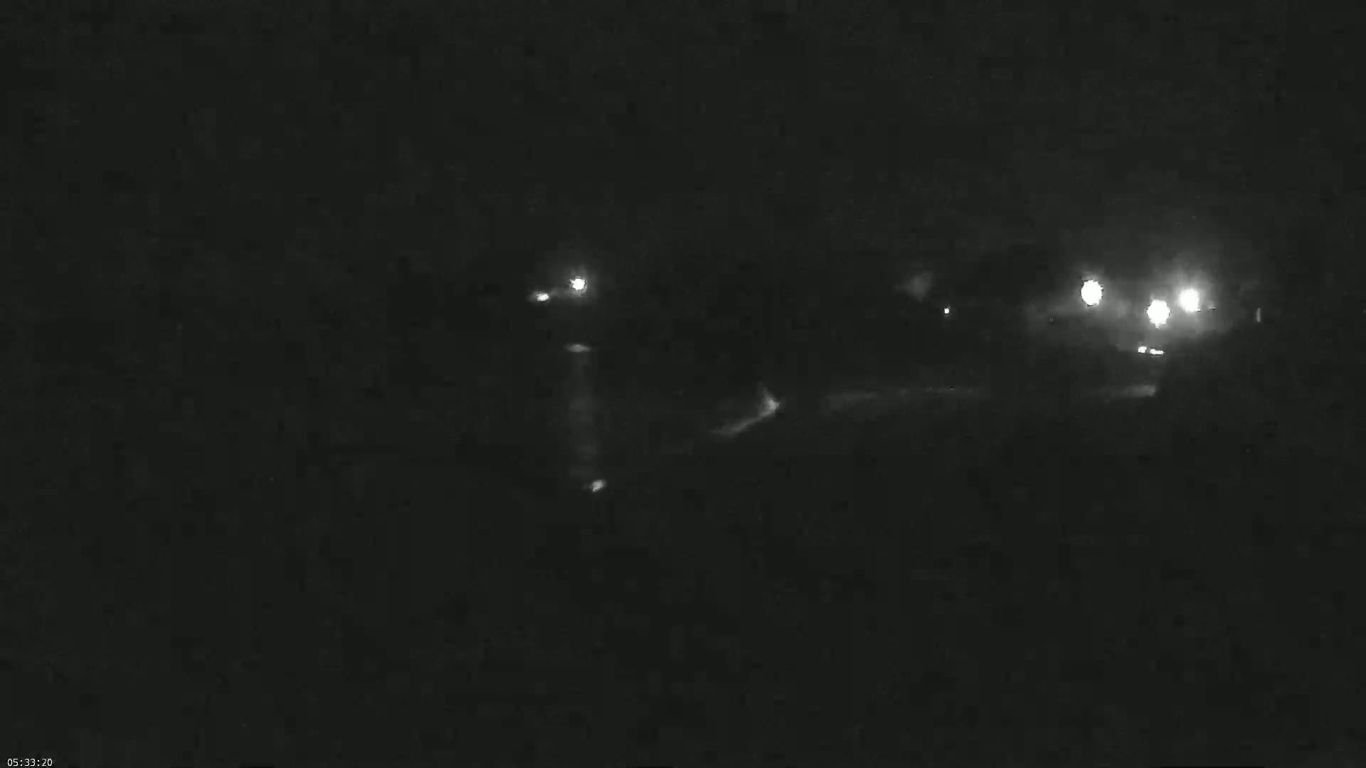 A nighttime, low-light view shows several distant lights likely from vehicles on a road.