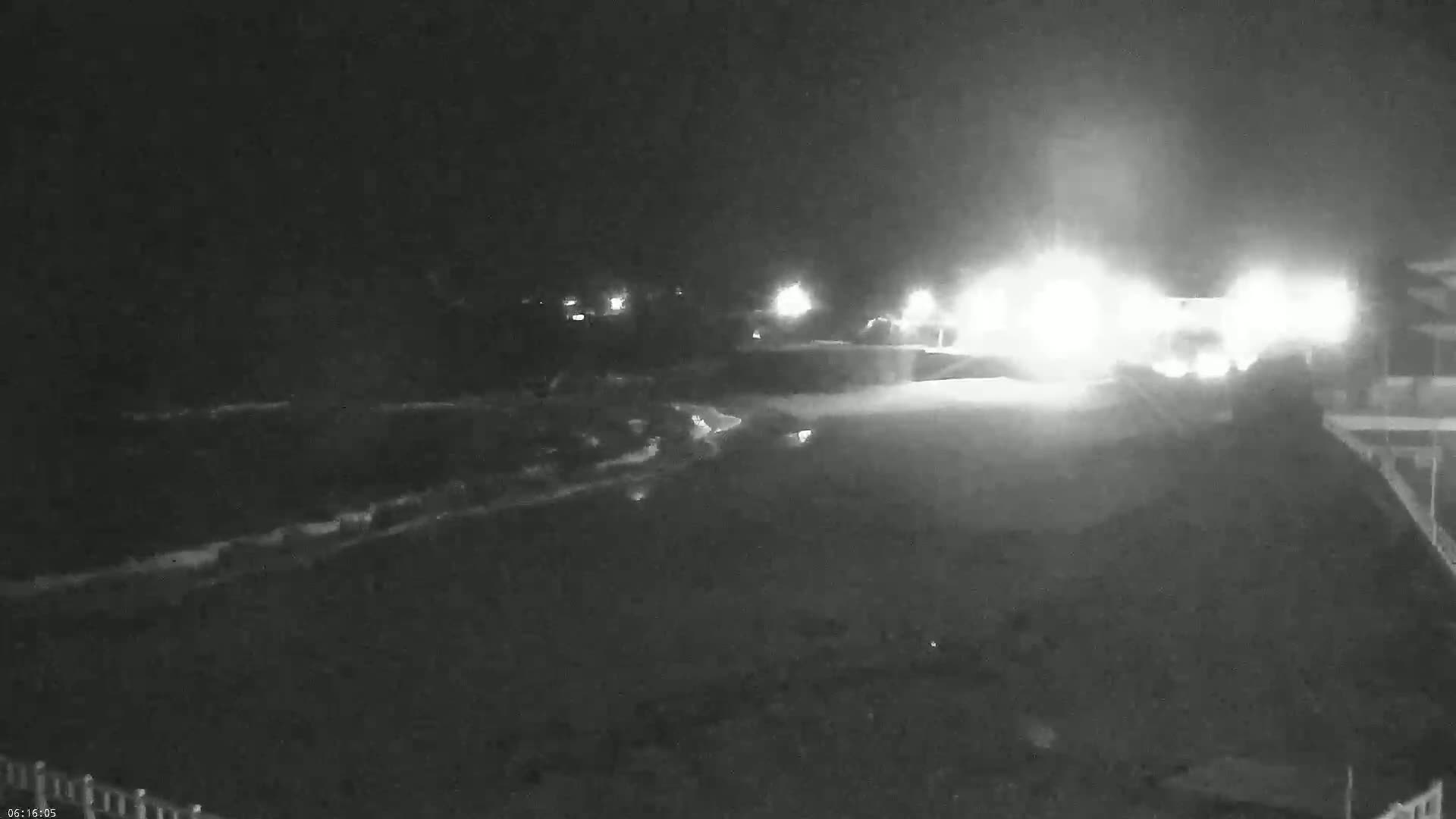 A nighttime, low-light view shows a dark, possibly paved area with some lights in the distance.