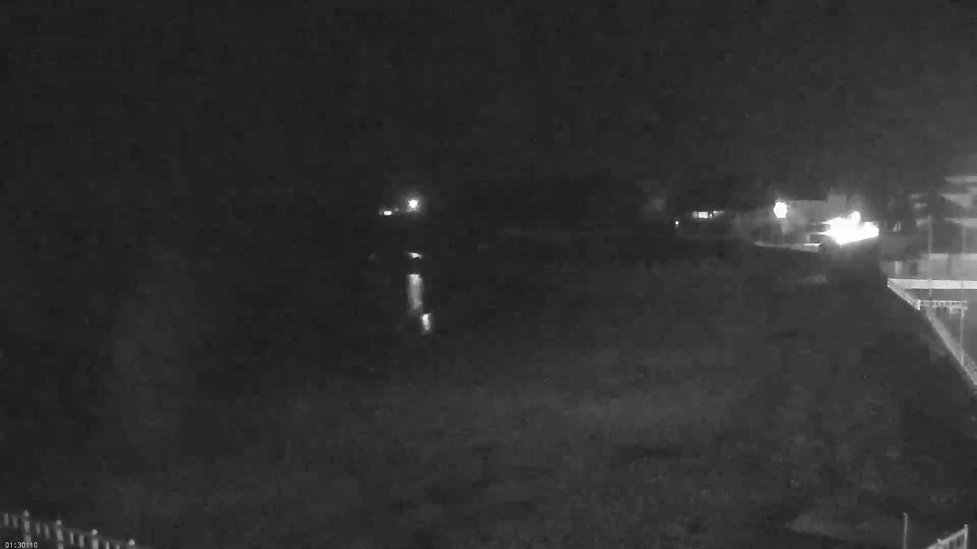 A nighttime, low-light image shows a dark, mostly empty landscape with a few distant lights.