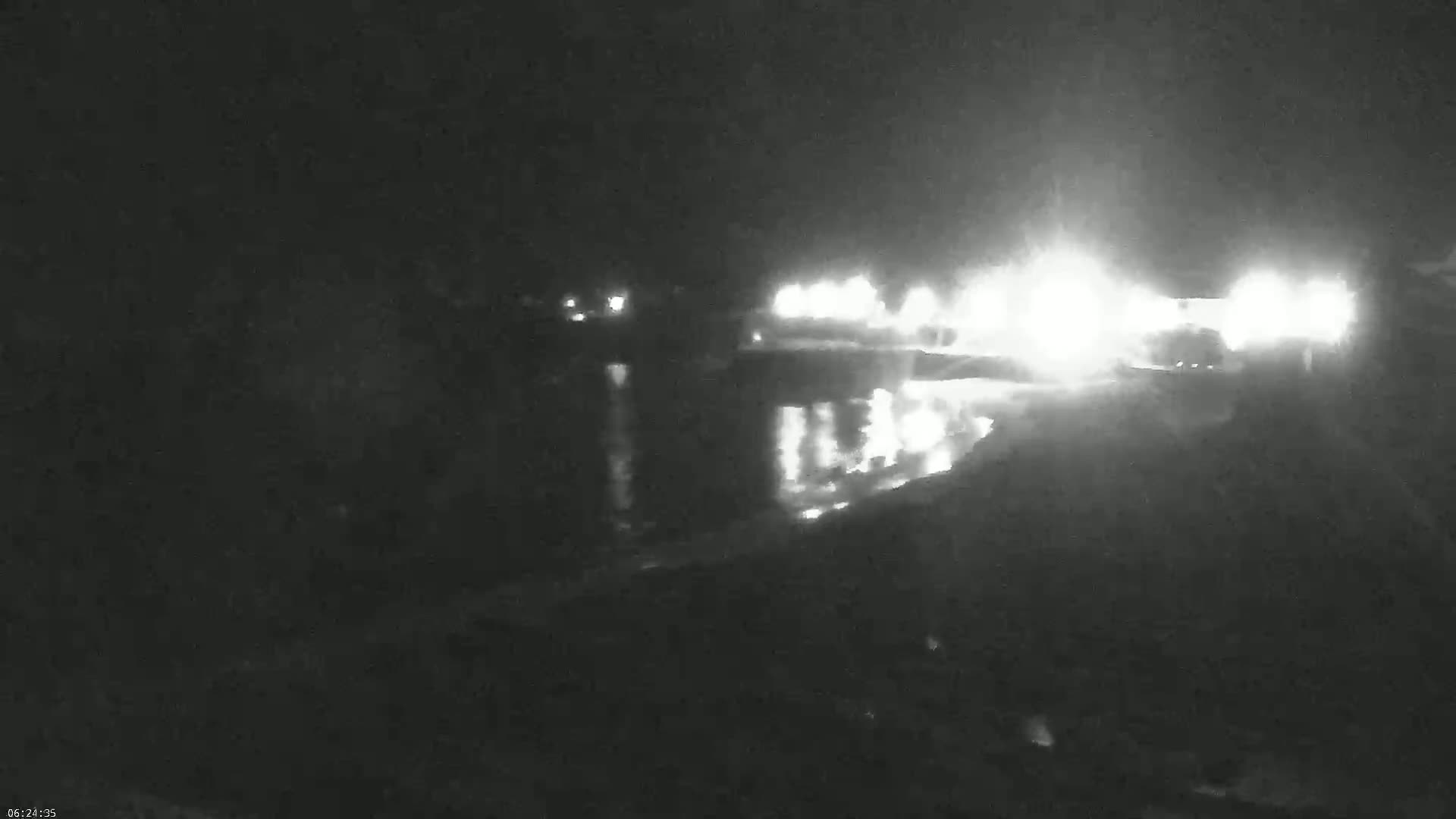 Bright lights from a distant structure are reflected on dark water at night.