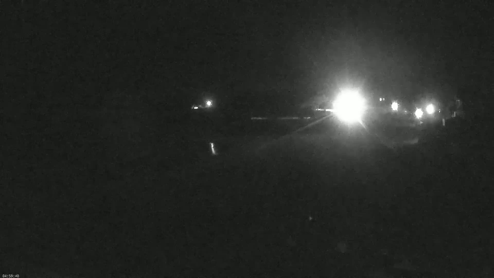 Headlights from several vehicles are visible on a dark road at night.