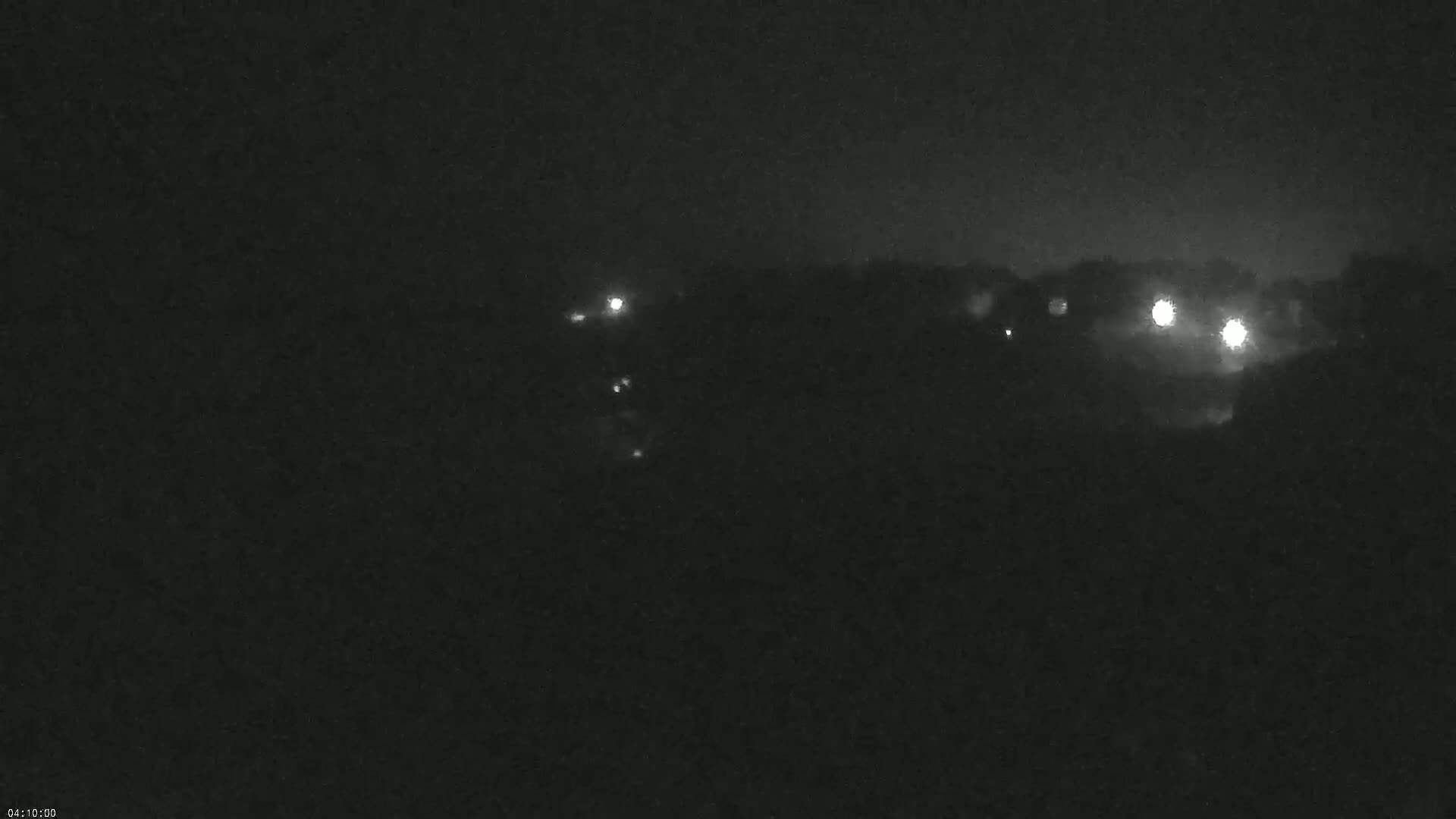 At night, several small lights are visible in the distance behind a dark, blurry landscape.