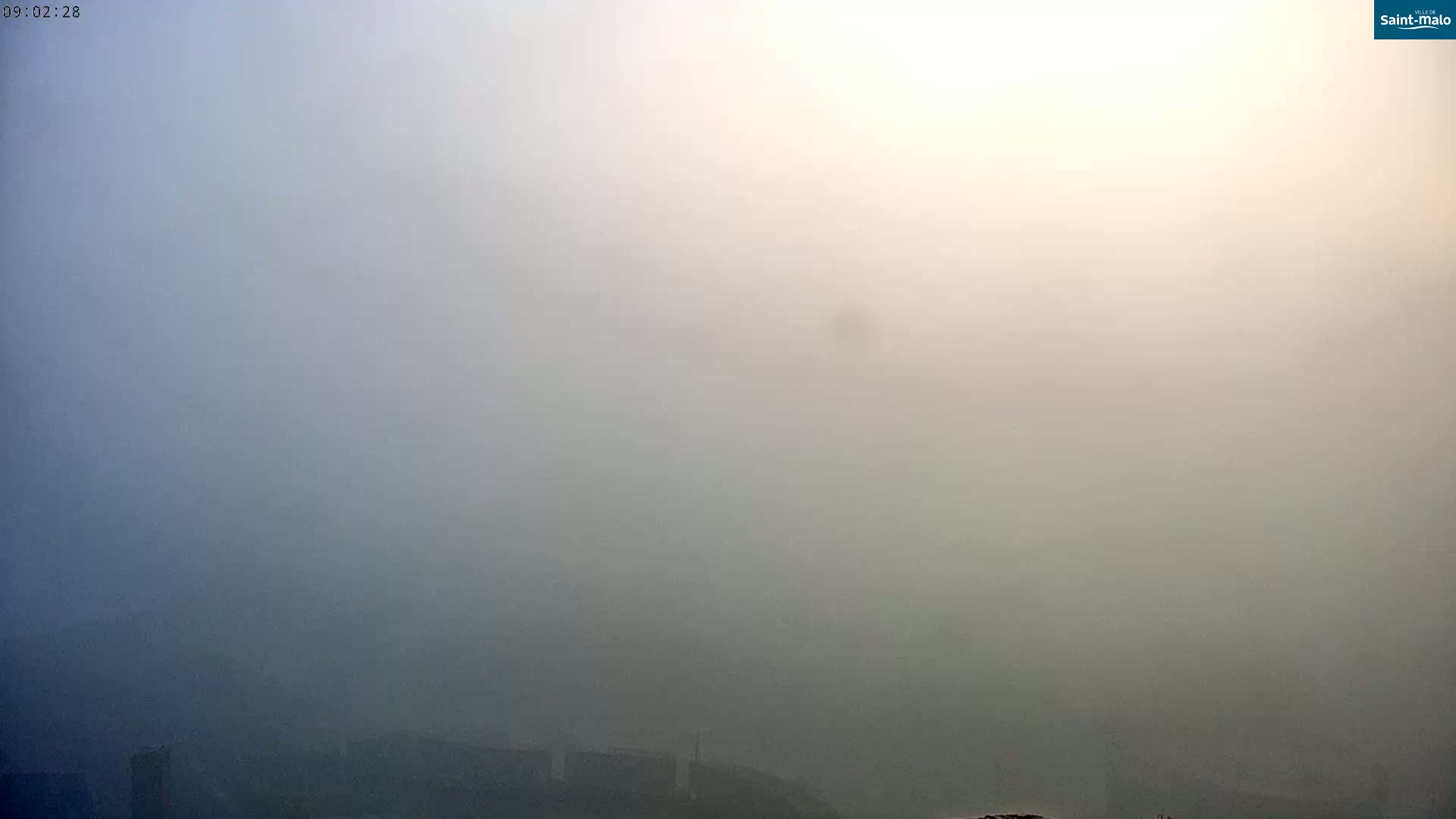 A thick fog obscures the view of a low-lying landscape.
