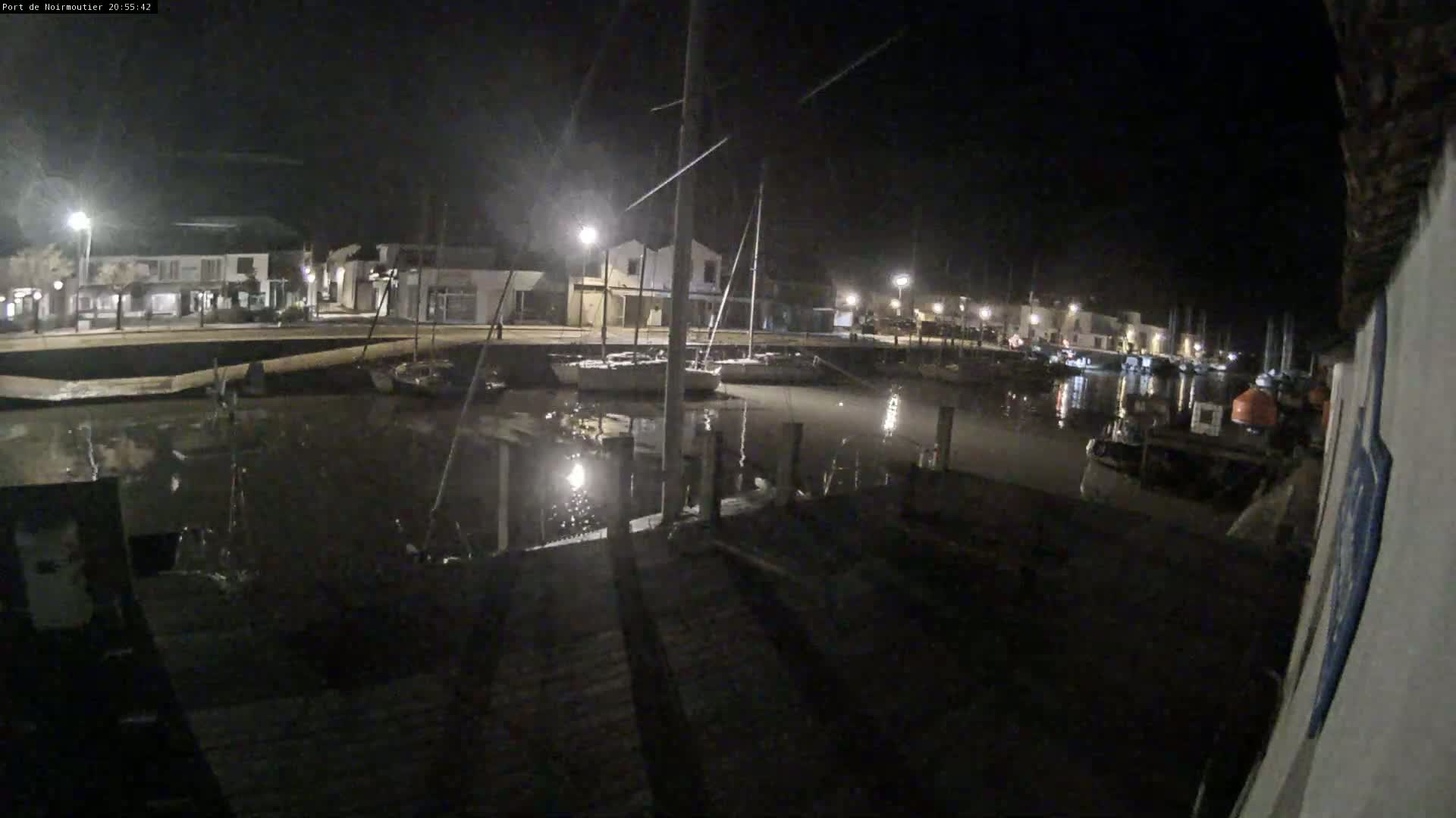 A nighttime view of a harbor with boats docked along a waterfront, illuminated by streetlights.