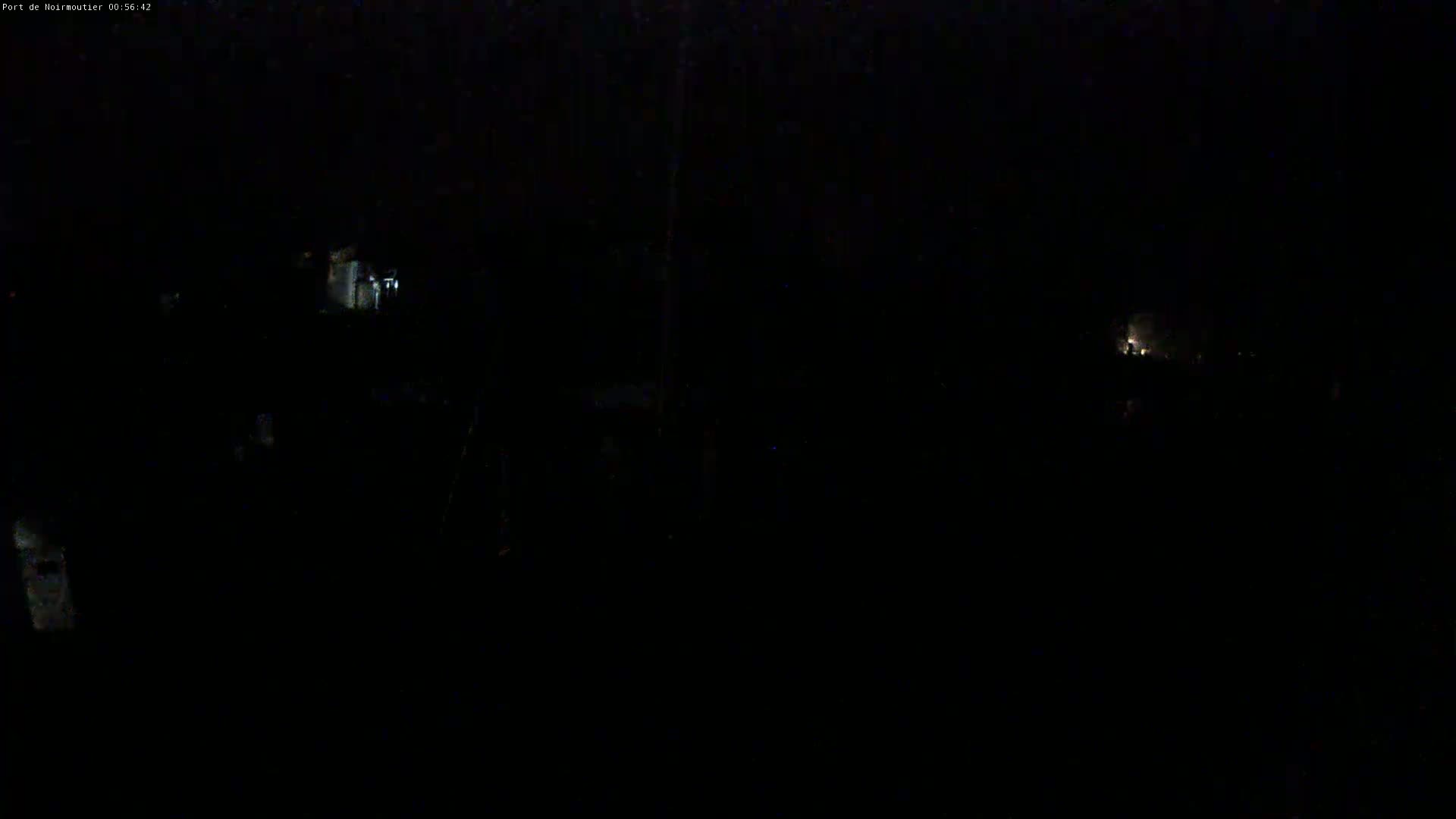 A very dark, nighttime scene shows indistinct shapes and faint lights in the distance.