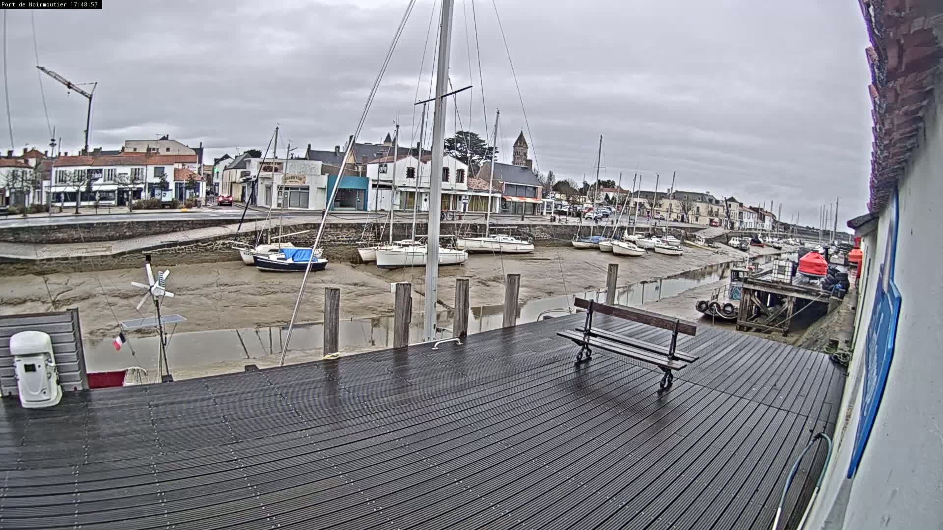 A harbor with sailboats docked at low tide on an overcast day.
