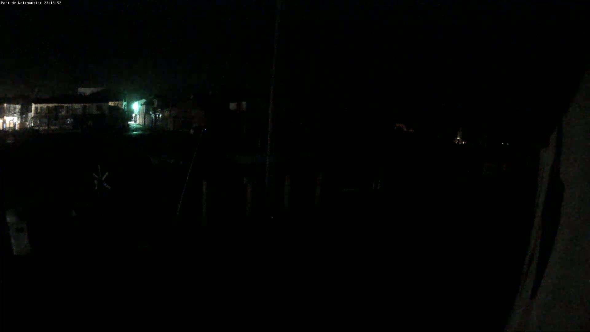 A dark, nighttime view of buildings and a possibly waterfront area with minimal light.