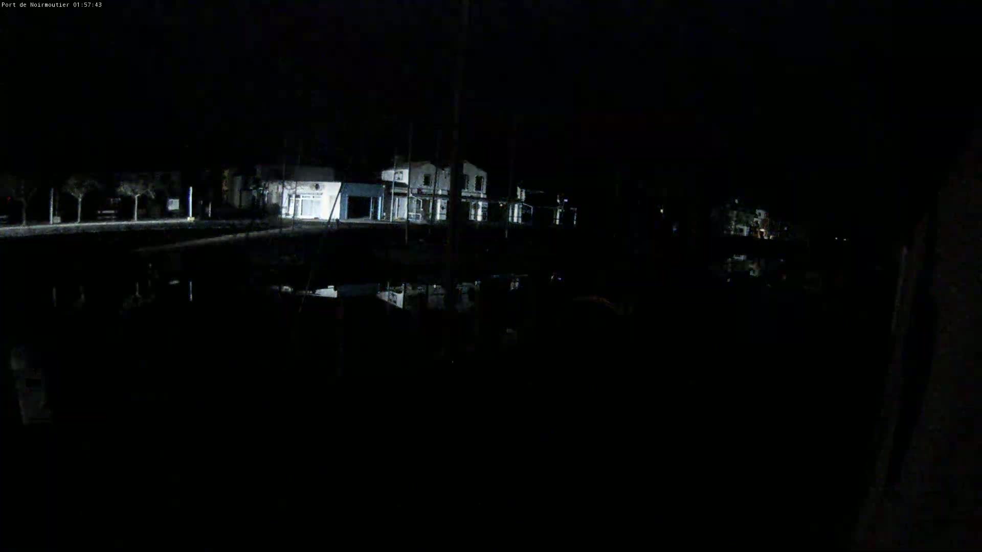 At night, a dark body of water reflects the lights of buildings on the opposite shore.