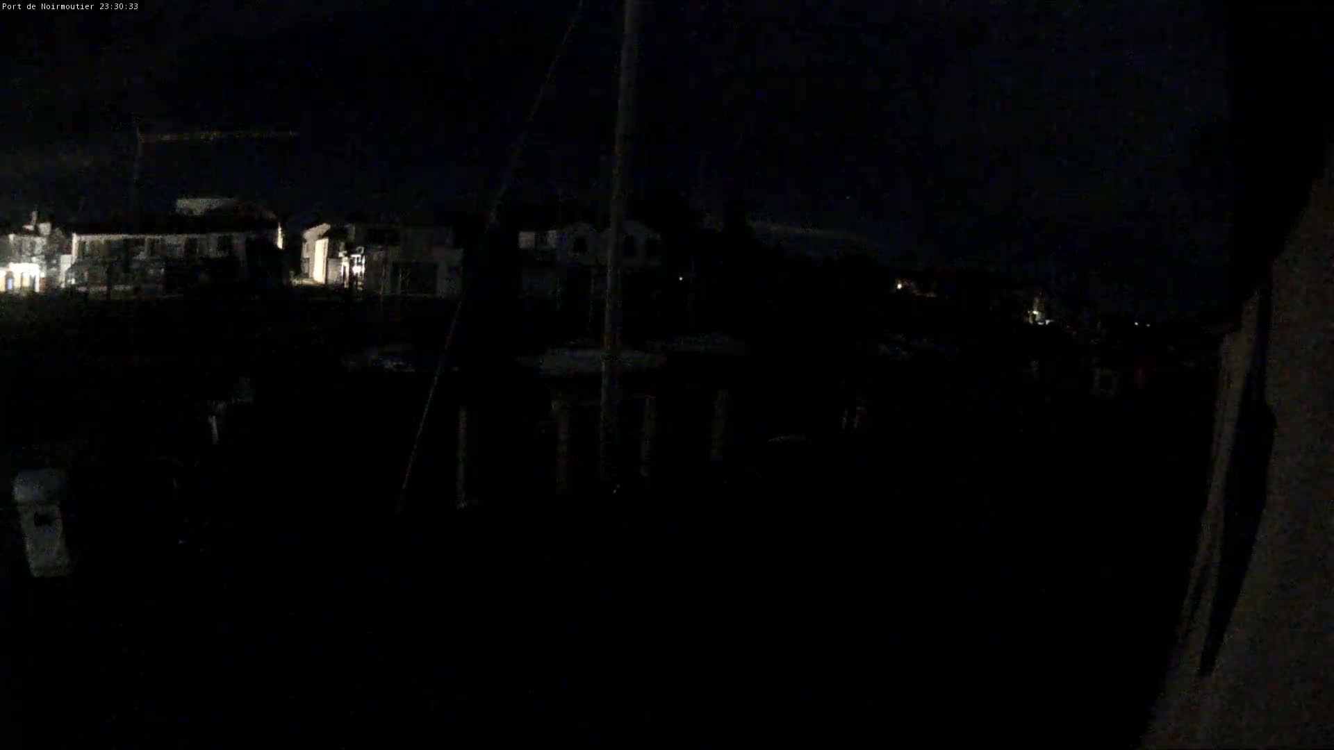 A dark, nighttime view of a harbor with dimly lit buildings in the background.