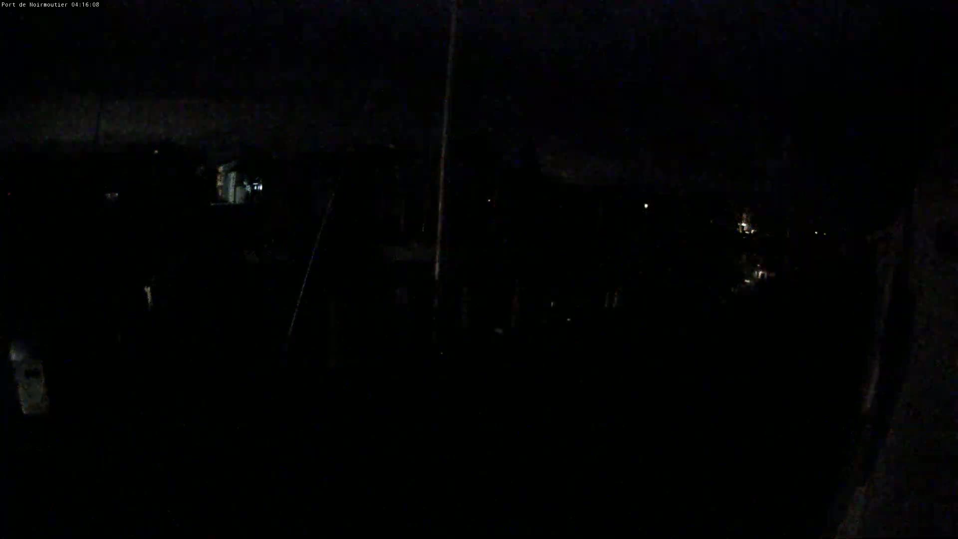 A dark, nighttime scene shows indistinct shapes and a few faint lights in the distance.