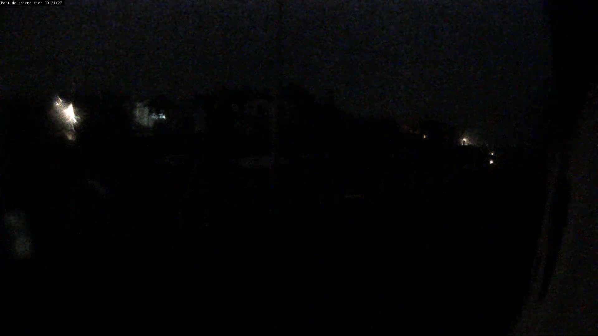 A dark, nighttime scene shows a few faint lights in the distance under an overcast sky.