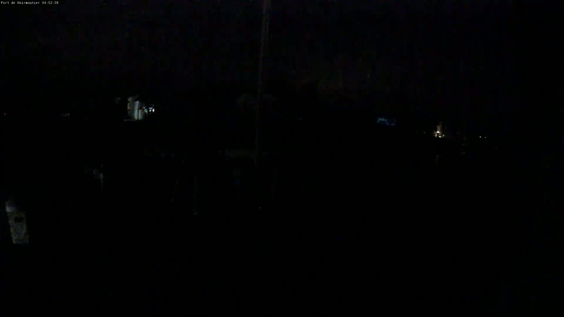 A very dark, nighttime scene shows faintly lit structures and possibly vehicles in the distance.