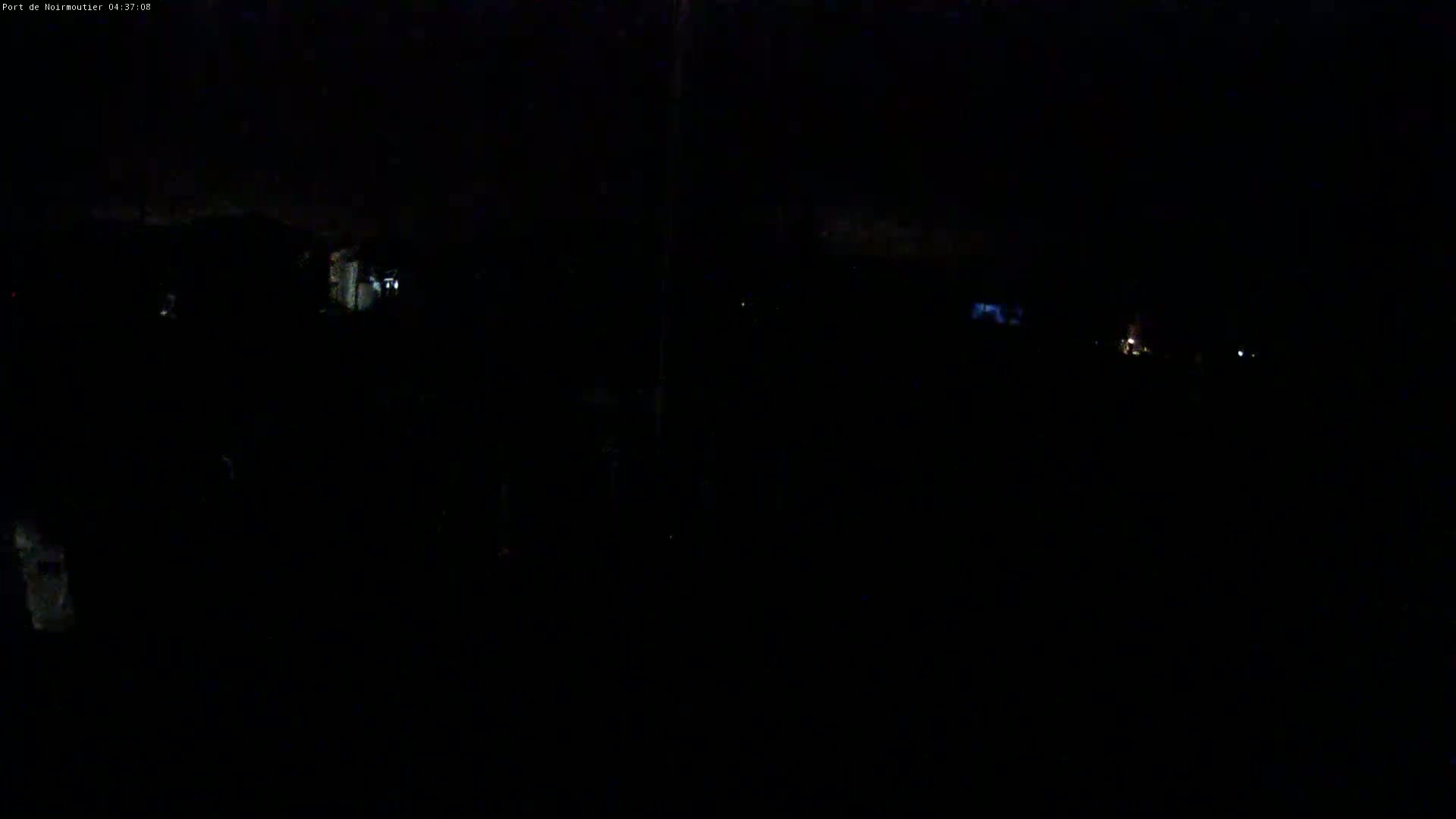 A nighttime, dark outdoor scene shows a few faint lights in the distance.