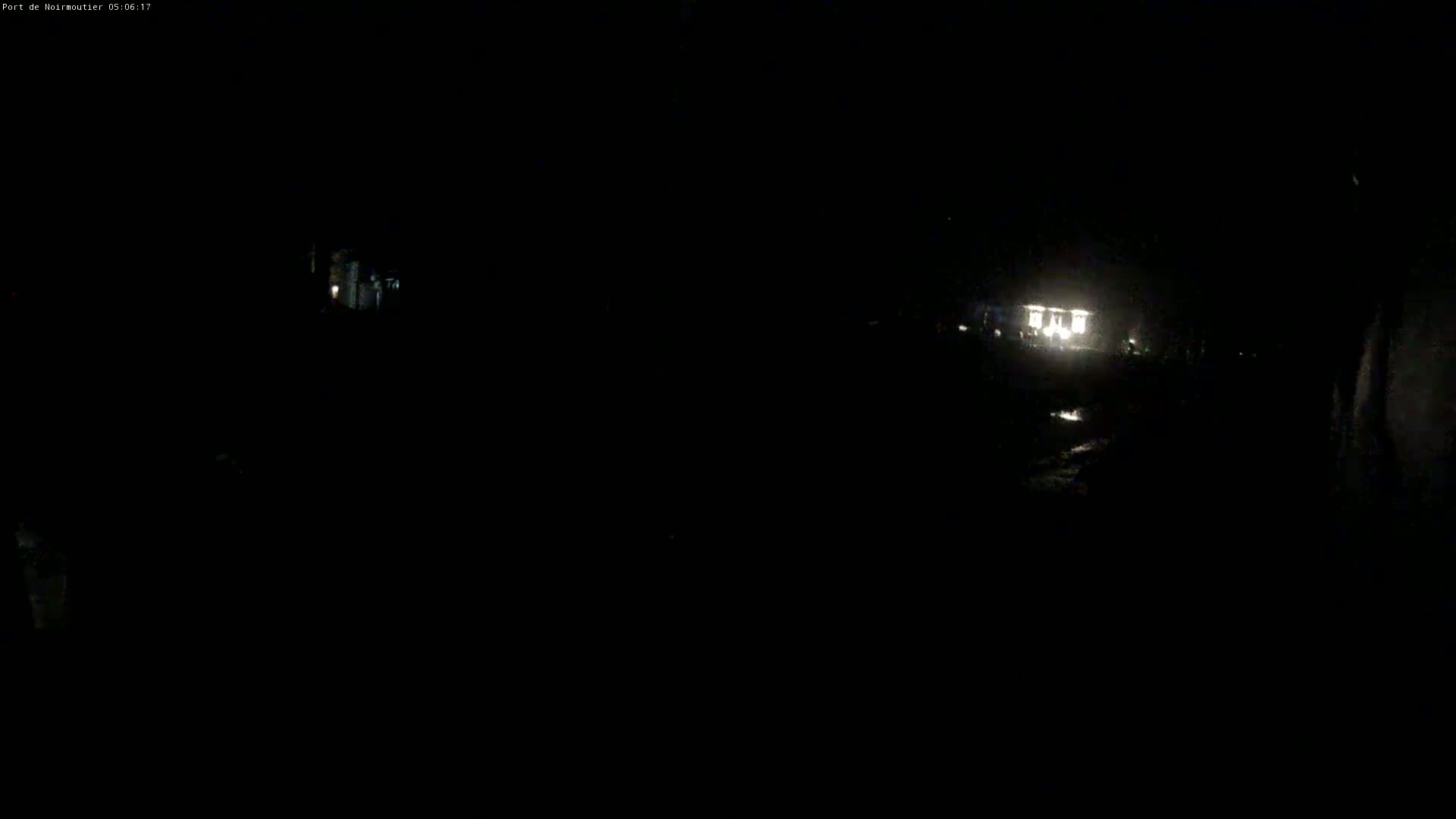 A dimly lit nighttime scene shows a building with lights on in the distance.