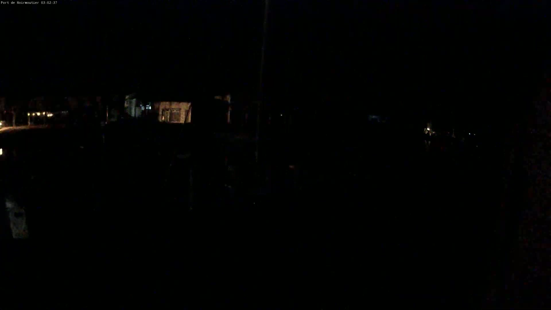 A very dark nighttime scene shows dimly lit buildings and faint lights in the distance.