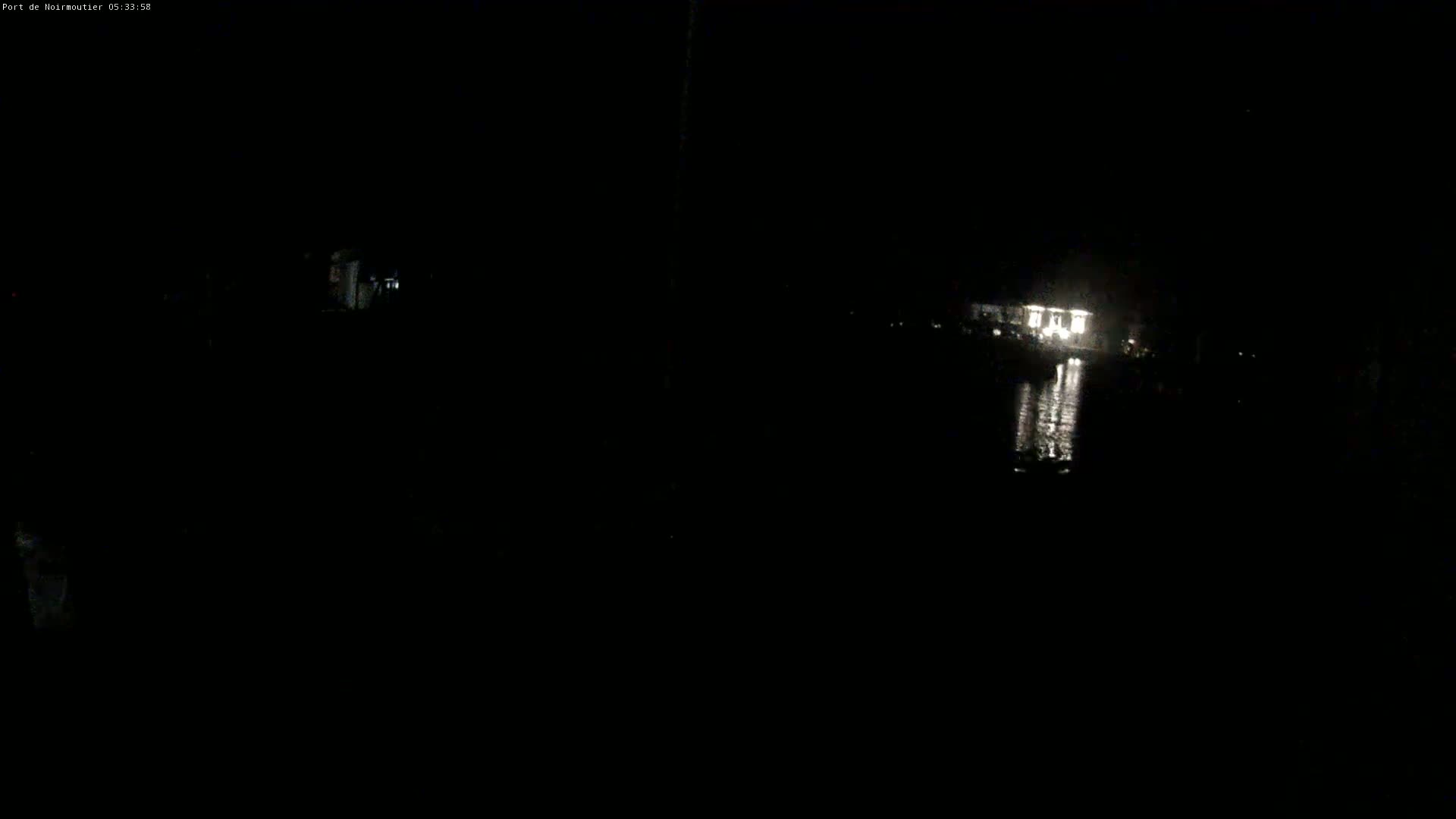 A dimly lit building is visible across a dark body of water at night.